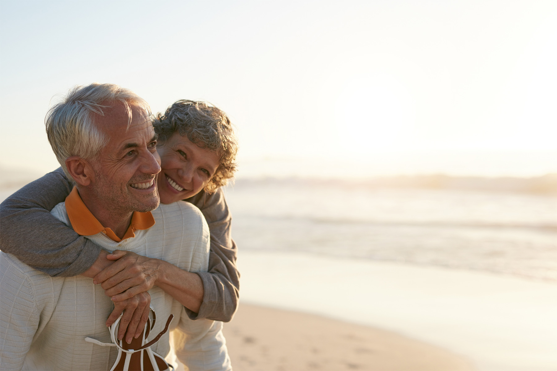Happy retired couple enjoying beach walk at sunset representing retirement planning, financial freedom, and long-term wealth management lifestyle