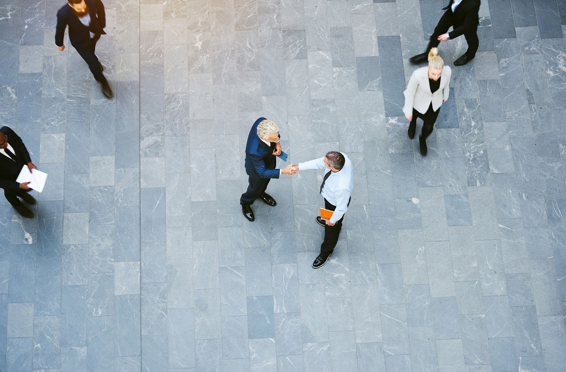 Overhead view of professionals shaking hands in a modern office representing business partnerships, trust, collaboration, and successful client relationships